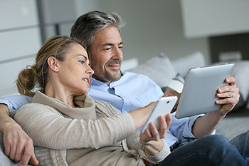 coppia sul divano guarda cellulare e tablet