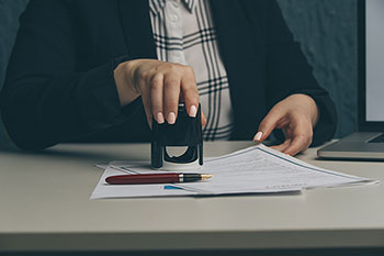 mano femminile che timbra un documento con un timbro autoinchiostrante