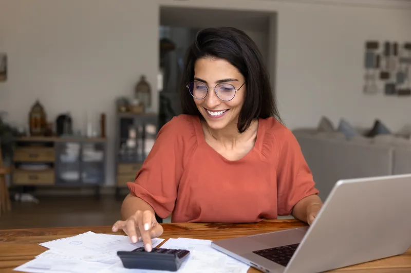 donna seduta alla scrivania che usa calcolatrice e pc