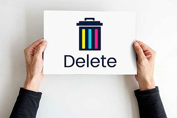 mani che tengono un foglio con stampato il simbolo del cestino e la scritta delete