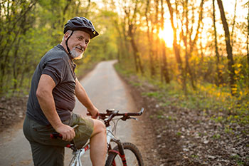 Uomo adulto in sella a una mountain bike in un sentiero nel bosco.