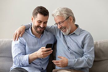 Padre e figlio sul divano guardano lo schermo del cellulare
