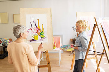 donna matura dipinge in una classe di pittura con la sua insegnante