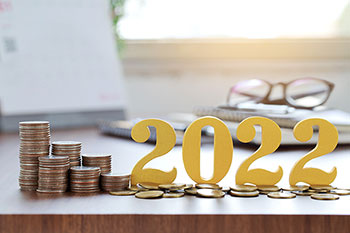 Scritta 3D raffigurante l'anno 2022 accanto a pile di monetine.